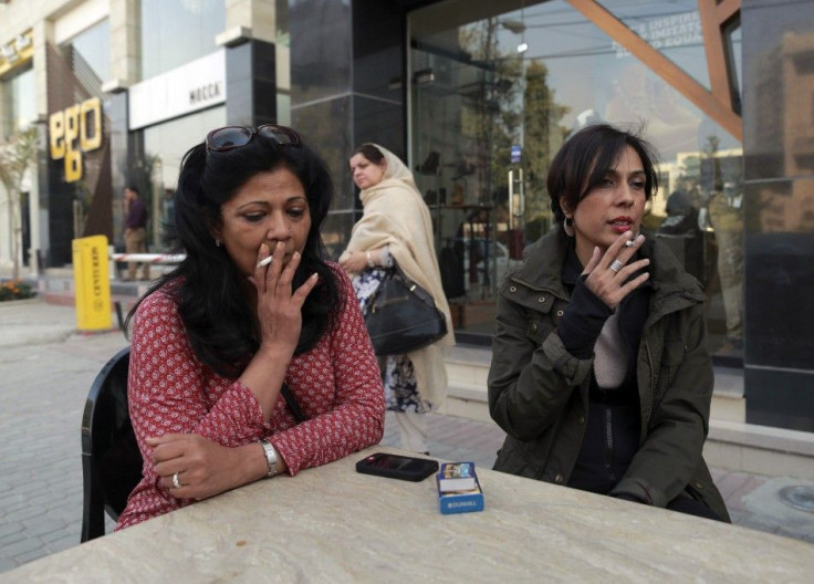 Pilates instructor Zainab Abbas smokes a cigarette as she sits with a friend after lunch in Lahore