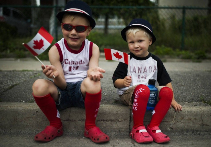 Boys wave the Canadian flags during Canada Day on the East York Canada Day Parade route in Toronto