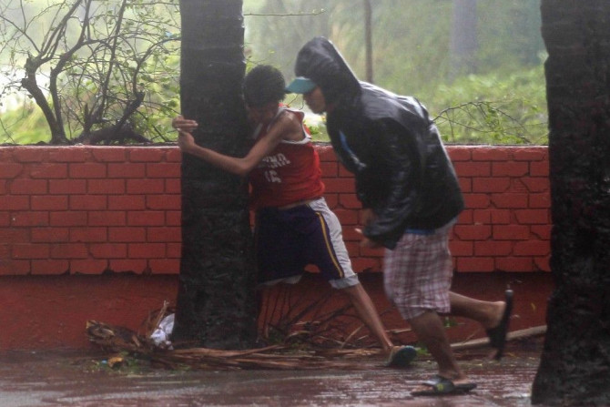A boy hugs a tree as he takes cover after strong winds brought by Typhoon Rammasun, locally called  Glenda, battered the capital, metro Manila July 16, 2014.  Philippine authorities evacuated almost 150,000 people from their homes and shuttered financial 