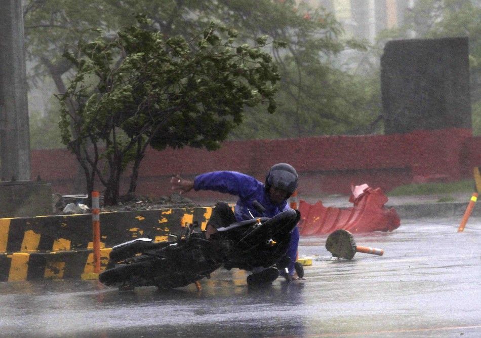 A motorcyclist falls down along a main road after strong winds brought  by Typhoon Rammasun, locally called Glenda, battered the capital, metro Manila July 16, 2014.  Philippine authorities evacuated almost 150,000 people from their homes and shuttered fi