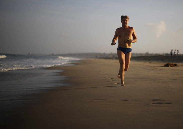 A man jogs on the sand next to the Pacific Ocean at sunrise