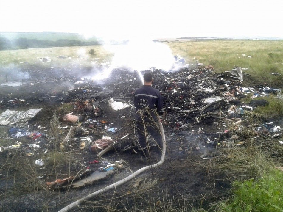 A man works at putting out a fire at the site of a Malaysia Airlines Boeing 777 