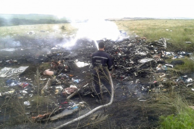 A man works at putting out a fire at the site of a Malaysia Airlines Boeing 777 