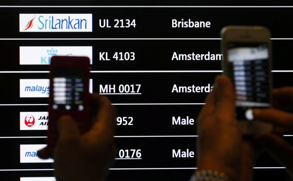 People take photos of a screen showing arrival details of Malaysia Airlines flight MH17 C at Kuala Lumpur International Airport in Sepang July 18, 2014. The Malaysian Boeing 777 airliner was brought down over eastern Ukraine on Thursday, killing all 295