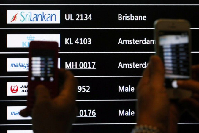 People take photos of a screen showing arrival details of Malaysia Airlines flight MH17 (C) at Kuala Lumpur International Airport in Sepang July 18, 2014. The Malaysian Boeing 777 airliner was brought down over eastern Ukraine on Thursday, killing all 295