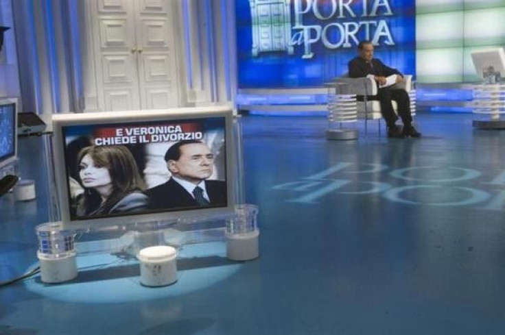 Italy&#039;s Prime Minister Silvio Berlusconi (R) sits near a television monitor showing images of him and his wife Veronica Lario during the taping of television program Porta a Porta (&#039;&#039;Door to door&#039;&#039; in Italian) in Rome May 5, 2009.