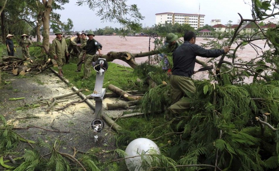 Local government workers clear away felled trees and a broken street lamp after strong winds and heavy rainfall from Typhoon Rammasun in Mong Cai July 19, 2014. Typhoon Rammasun triggered heavy rain and strong winds in northern Vietnam as it made landfall