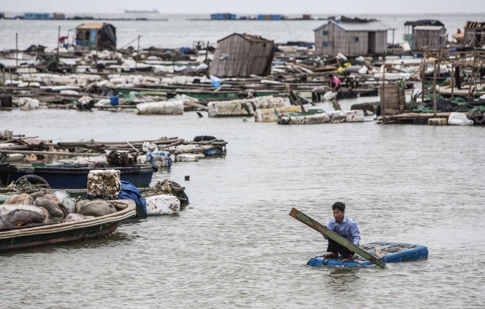 A fisherman paddles a makeshift boat to check his fish farms after Typhoon Rammasun hit Leizhou, Guangdong province July 19, 2014. A super typhoon has killed at least fourteen people in China since making landfall on Friday afternoon, state media said on 