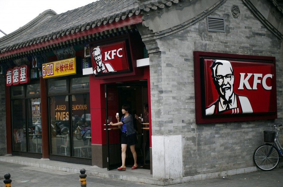 A woman holding an ice cream walks out of a KFC restaurant in Beijing July 17, 2014. 