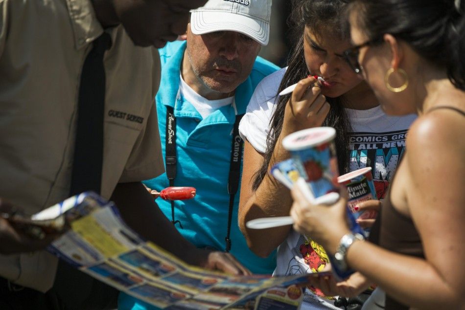 Tourists eat ice cream as they talk to a bus company vendor on a warm summer day in New York July 2, 2014. 