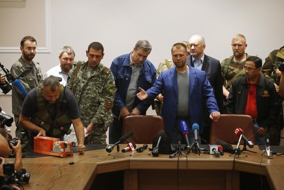 Senior Ukrainian separatist leader Aleksander Borodai centre R gestures as a rebel L places the black boxes of Malaysia Airlines flight MH17 on a desk, during their handover to Colonel Mohamed Sakri R of the Malaysian National Security Council, in D