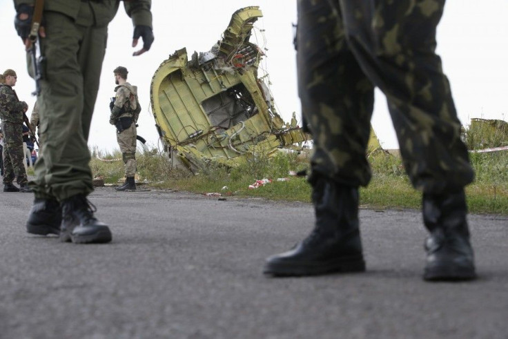 Armed pro-Russian separatists stand guard as monitors from the Organization for Security and Cooperation in Europe (OSCE) and members of a Malaysian air crash investigation team inspect the crash site of Malaysia Airlines Flight MH17, near the village of 