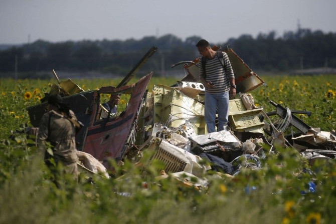 A Malaysian air crash investigator (R) inspects the crash site of Malaysia Airlines Flight MH17, near the village of Rozsypne, Donetsk region, July 22, 2014. A train carrying the remains of many of the 298 victims of Malaysia Airlines flight MH17 arrived 