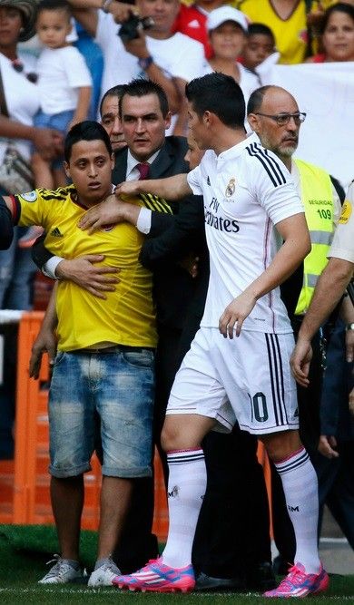 A fan tries to embrace Colombias soccer player James Rodriguez during his presentation at the Santiago Bernabeu stadium in Madrid