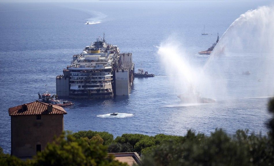 Tugboats spays water in farewell to the cruise liner Costa Concordia during the refloat operation maneuvers at Giglio Island July 23, 2014. Maneuvers began early on Wednesday to remove the rusty hulk of the Costa Concordia cruise liner from the Italian is