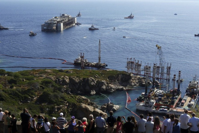 People watch the cruise liner Costa Concordia moving anticlockwise during the refloat operation maneuvers at Giglio Island July 23, 2014. Maneuvers began early on Wednesday to remove the rusty hulk of the Costa Concordia cruise liner from the Italian isla