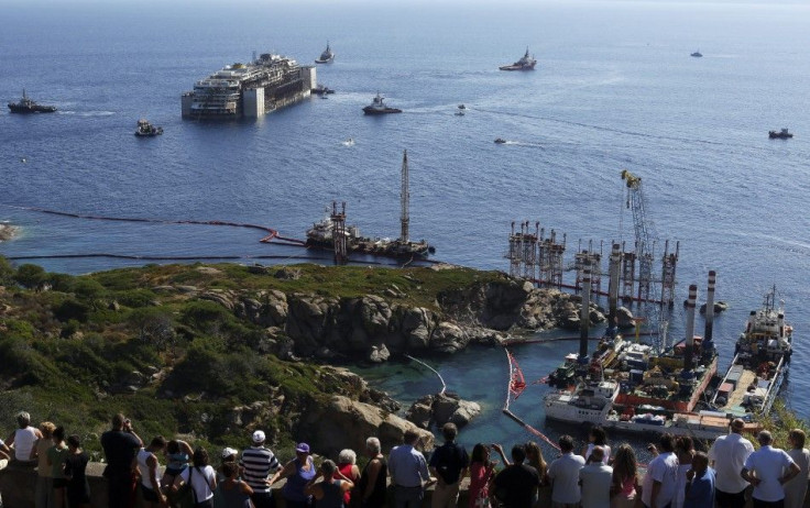 People watch the cruise liner Costa Concordia moving anticlockwise during the refloat operation maneuvers at Giglio Island July 23, 2014. Maneuvers began early on Wednesday to remove the rusty hulk of the Costa Concordia cruise liner from the Italian isla