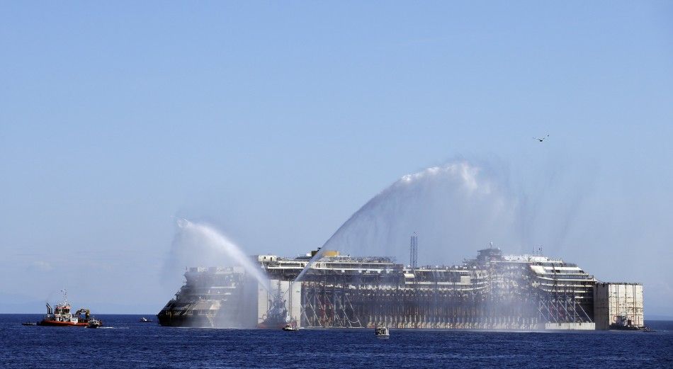 REFILE - CORRECTING GRAMMAR Tugboats spay water in farewell  to the cruise liner Costa Concordia during the refloat operation maneuvers at Giglio Island July 23, 2014. Maneuvers began early on Wednesday to remove the rusty hulk of the Costa Concordia crui