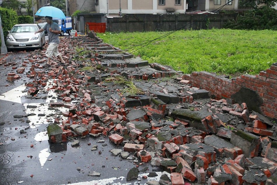 A man walks over fallen bricks from a wall that was blown over by strong winds from Typhoon Matmo which hit Taiwan, in Taipei July 23, 2014. Typhoon Matmo slammed into Taiwan on Wednesday with heavy rains and strong winds, shutting financial markets and s