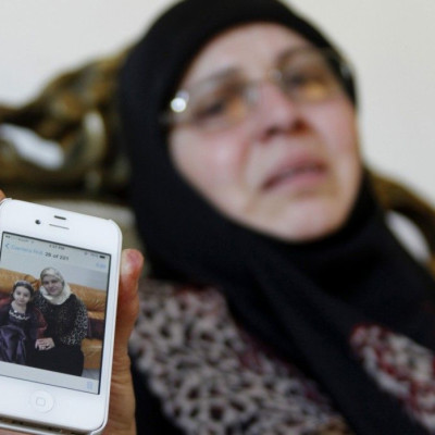 The sister-in-law of Lebanese passenger Randa Daher reacts as she holds her mobile phone displaying a picture of Randa and one of her children at her home in the southern Lebanese village of Srifa July 24, 2014. According to local media, Randa and her chi