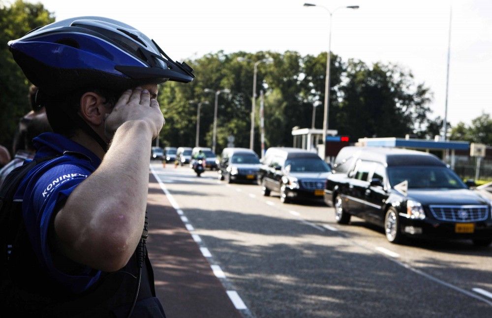 A policeman salutes as the convoy of hearses with the remains of the victims of Malaysia Airlines MH17 downed over rebel-held territory in eastern Ukraine drives past on its way to a military base in Hilversum July 24, 2014.
