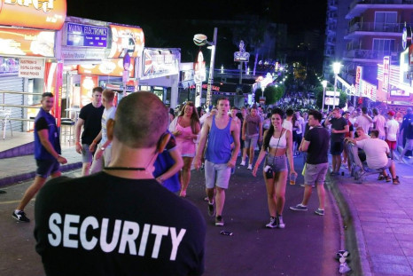 A security worker looks at tourists walking at Punta Ballena street in Magaluf, on the Spanish Balearic island of Mallorca, July 26, 2014. The Punta Ballena area has been famous since the 70's for its nightlife and is a favourite destination for main