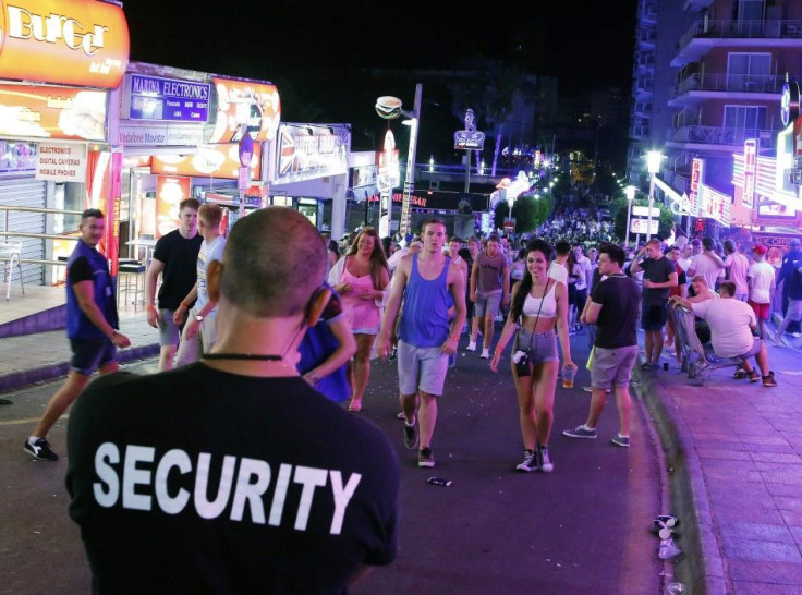 A security worker looks at tourists walking at Punta Ballena street in Magaluf, on the Spanish Balearic island of Mallorca, July 26, 2014. The Punta Ballena area has been famous since the 70's for its nightlife and is a favourite destination for main