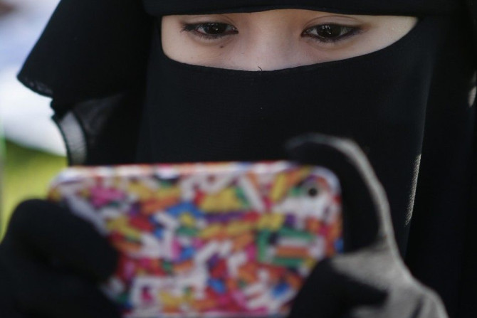 A Filipino Muslim looks at her mobile phone while waiting for morning prayers to begin, during the celebration of Eid al-Fitr in Manila