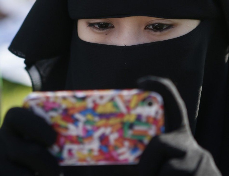 A Filipino Muslim looks at her mobile phone while waiting for morning prayers to begin, during the celebration of Eid al-Fitr in Manila