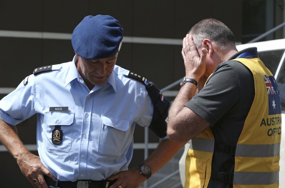 Head of Australian Federal Police mission Commander Brian McDonald R touches his face as Dutch police officer Kuijs stands nearby after returning to Donetsk, July 28, 2014. Fighting forced international experts to abandon plans, for a second day running