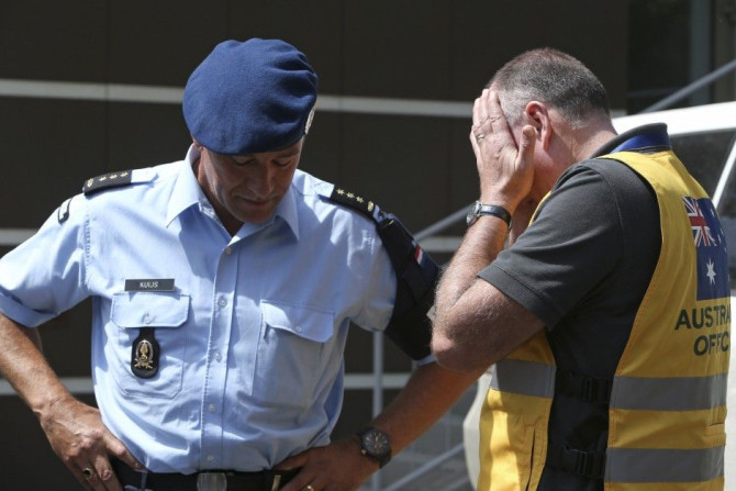 Head of Australian Federal Police mission Commander Brian McDonald (R) touches his face as Dutch police officer Kuijs stands nearby after returning to Donetsk, July 28, 2014. Fighting forced international experts to abandon plans, for a second day running