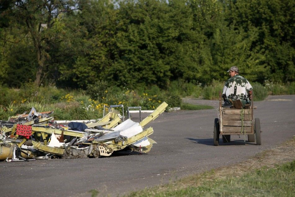 A local resident rides past debris at the site of Thursdays Malaysia Airlines Boeing 777 plane crash, near Petropavlivka village in the Donetsk region July 23, 2014.  The bodies of the first victims from a Malaysian airliner shot down over Ukraine last w