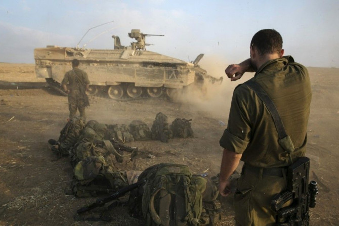 An Israeli soldier stands at a staging area after crossing back into Israel from Gaza