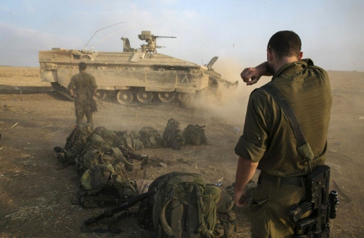 An Israeli soldier stands at a staging area after crossing back into Israel from Gaza