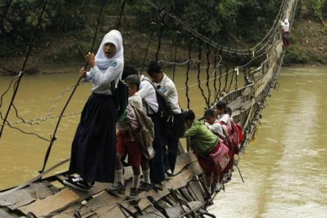 Students hold on to the side steel bars of a collapsed bridge as they cross a river to get to school at Sanghiang Tanjung village in Lebak regency, Indonesia&#039;s Banten village, January 19, 2012.