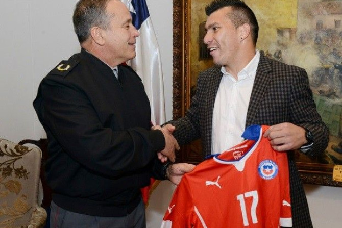 Chile&#039;s national soccer player Gary Medel (R) presents his jersey to the Commander in Chief of the Chilean Army, General Humberto Oviedo during a meeting in Santiago July 4, 2014. The Chilean Army on Friday honored Medel for his role in the World Cup