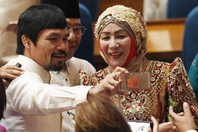 Manny Pacquiao (L), Philippine lawmaker and world boxing champion, uses his mobile phone to take &quot;selfies&quot; with fellow lawmakers before the start of the joint session of the 16th Congress at the House of Representatives of the Philippines in Que