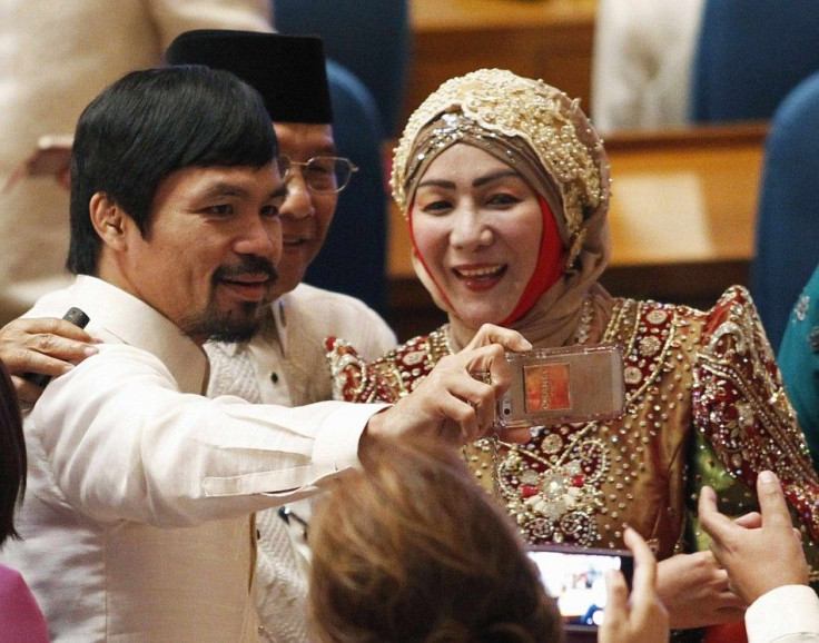 Manny Pacquiao (L), Philippine lawmaker and world boxing champion, uses his mobile phone to take &quot;selfies&quot; with fellow lawmakers before the start of the joint session of the 16th Congress at the House of Representatives of the Philippines in Que