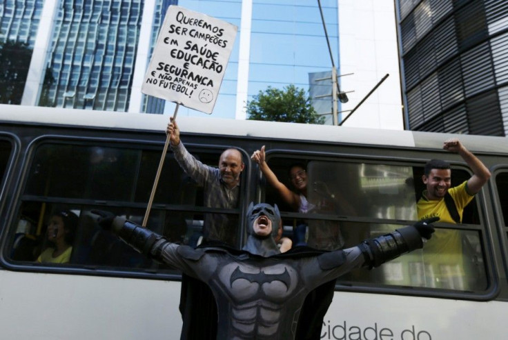 An anti-government demonstrator dressed as Batman yells slogans accompanied by passengers on a bus, during a protest against the 2014 World Cup in Rio de Janeiro June 12, 2014.