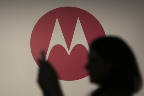 A Woman Takes A Picture In Front Of A Motorola Logo.