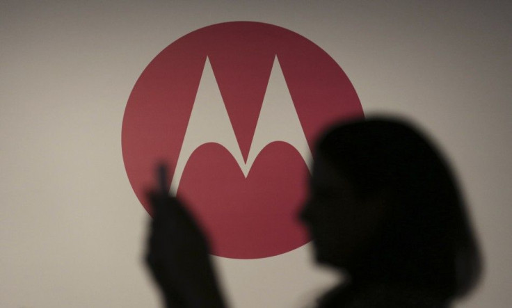 A Woman Takes A Picture In Front Of A Motorola Logo.