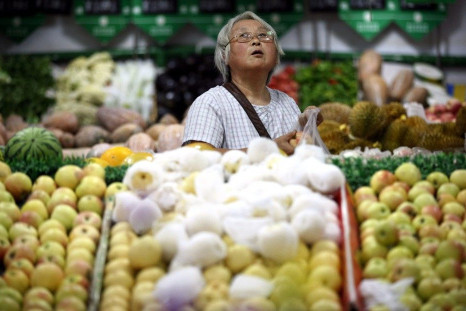 A customer looks up at price tags as she selects fruits at a supermarket in Ma&#039;anshan,
