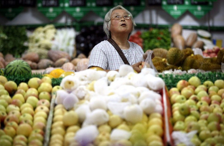 A customer looks up at price tags as she selects fruits at a supermarket in Ma&#039;anshan,