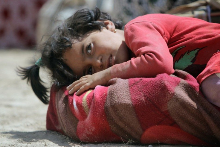 A displaced child from minority Yazidi sect, fleeing violence from forces loyal to Islamic State in Sinjar town, rests as she makes her way, on the outskirts of Sinjar mountain