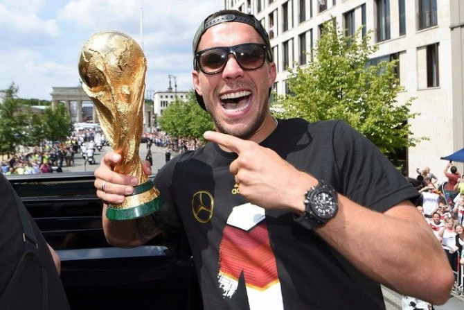 Germany's Lukas Podolski poses with the World Cup trophy during celebrations to mark the team's 2014 Brazil World Cup victory in Berlin July 15, 2014. Germany's victorious soccer team led by coach Joachim Loew returned home on Tuesday after