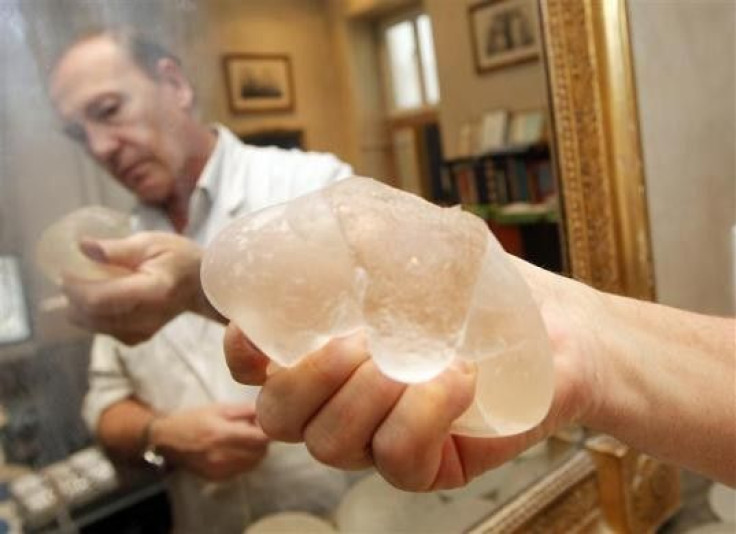 Plastic surgeon Denis Boucq poses at his office in a clinic in Nice December 16, 2011, holding a defective silicone gel breast implant, which was removed from a patient and manufactured by French company PIP.