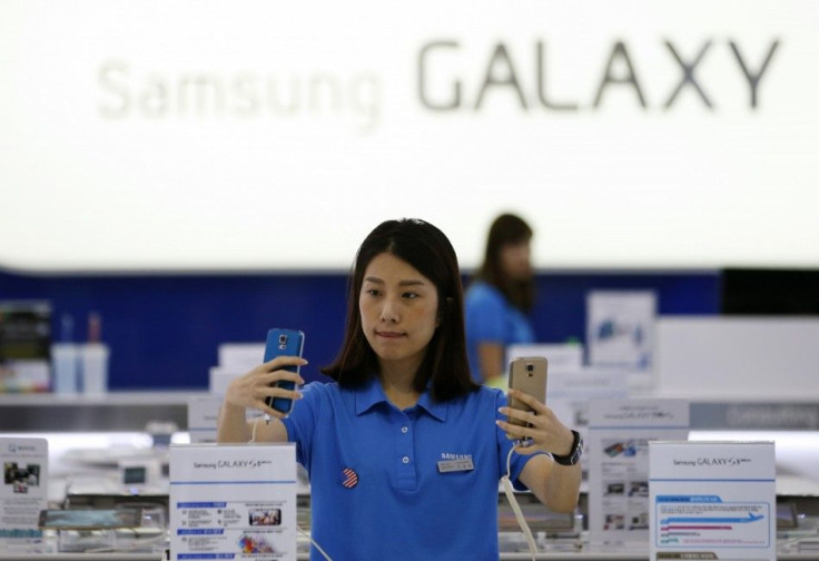 A sales assistant checks Samsung Electronics' Galaxy S5 smartphones at a shop in Seoul