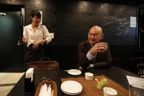 Shiro Fukai, 48, drinks distilled spirit next to manager Yoshiko Toyoda (L) at the Otasuke &quot;izakaya&quot; style pub and restaurant in Tokyo May 8, 2014.