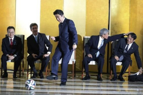 Japan&#039;s Prime Minister Shinzo Abe kicks a soccer ball during a meeting with Brazilian soccer players in Brasilia