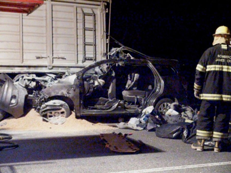 A TV still image shows a firefighter standing next to a car, trapped underneath a truck, in which three relatives of Pope Francis were killed near James Craik